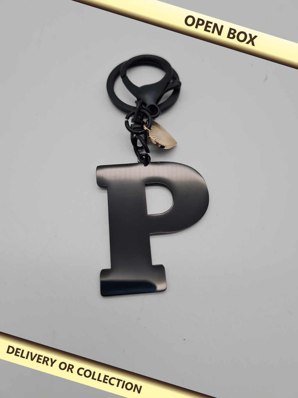 Letter P initial keyring and bag charm — photograph 1 — Open box; auction delivery information shown on image