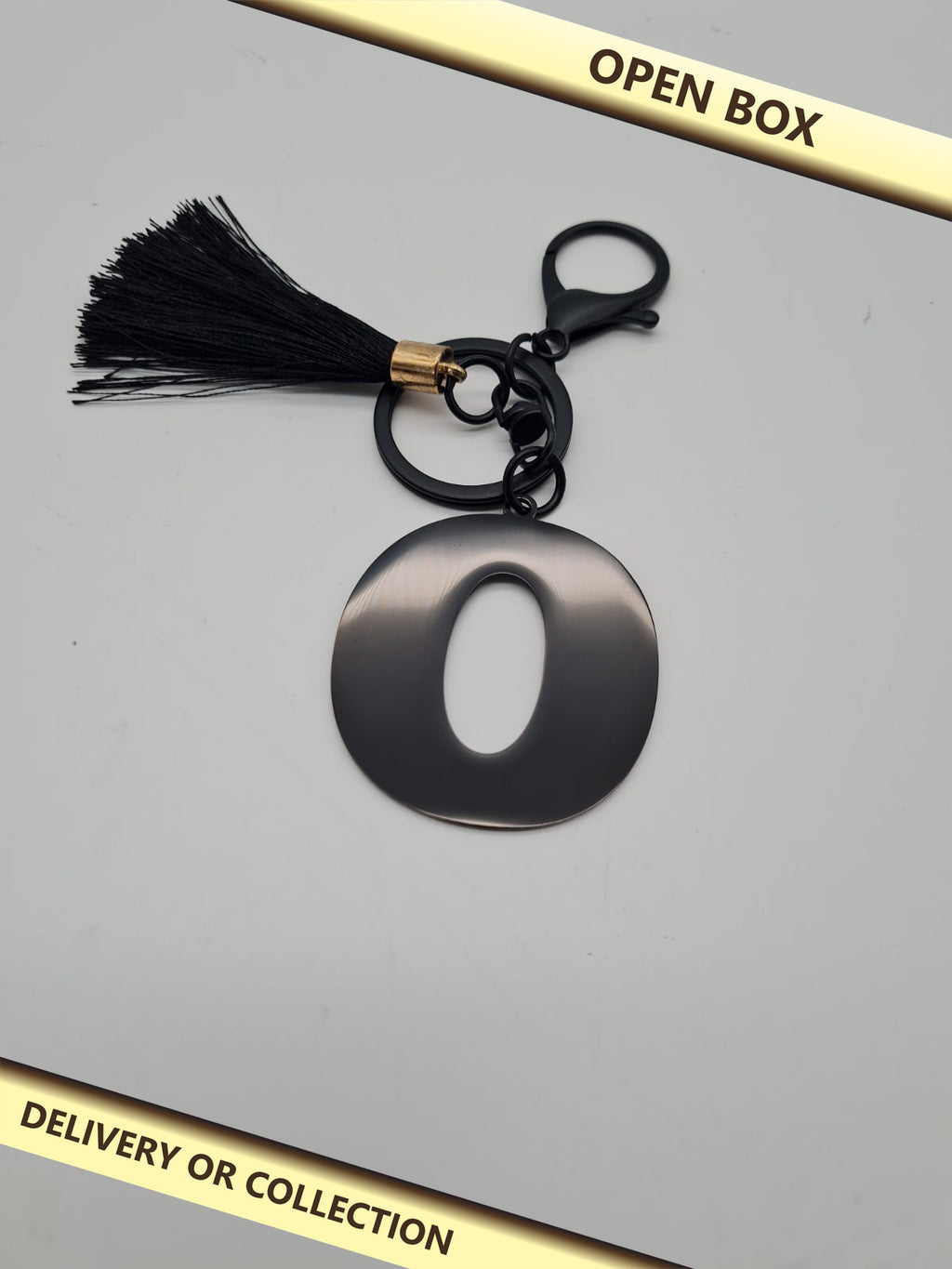 Letter O Initial Keyring with Tassel — photograph 1 — Open box; auction delivery information shown on image