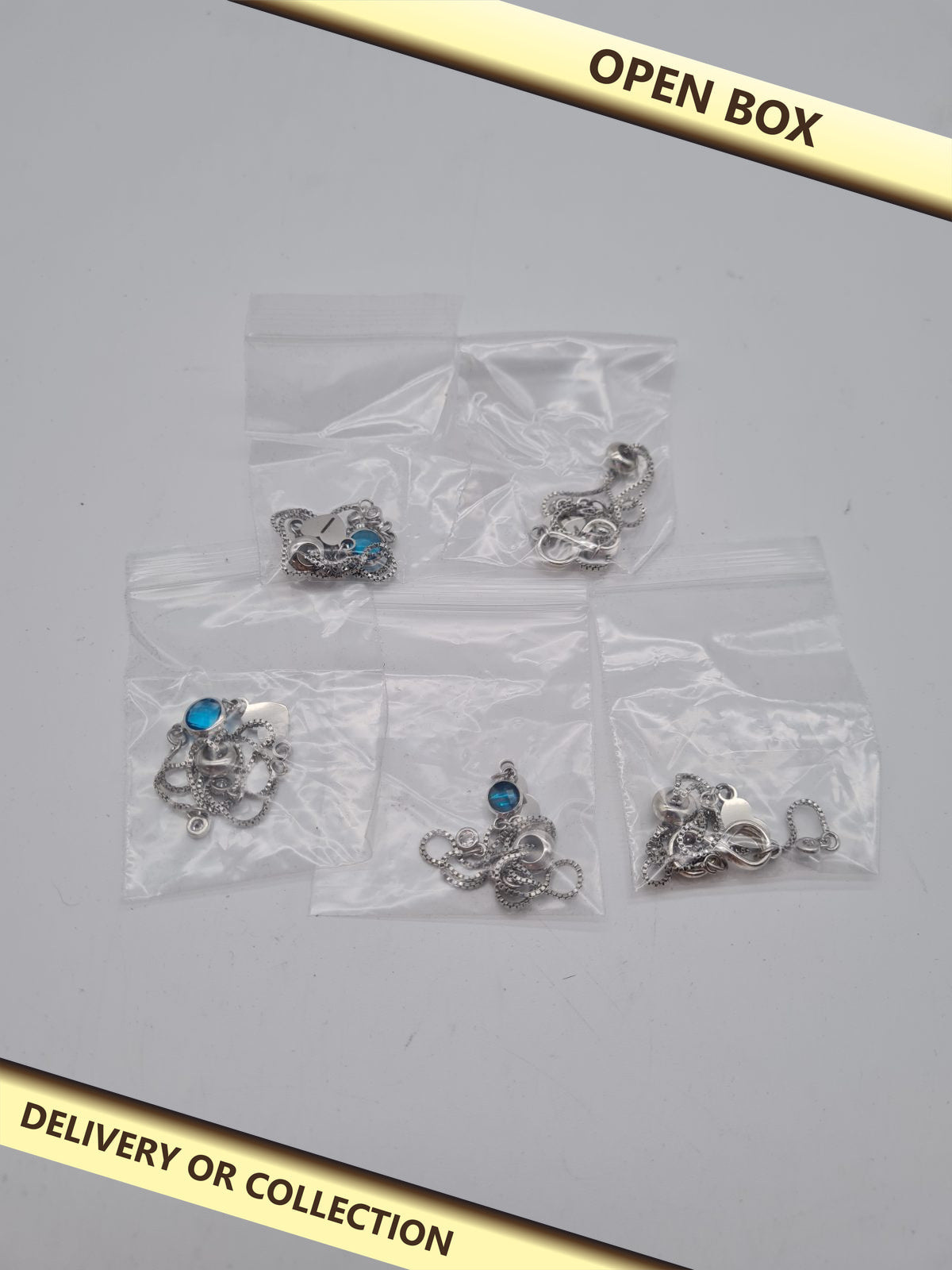 Set of Five Infinity Pendant Chain Bracelets — photograph 1 — Open box; auction delivery information shown on image