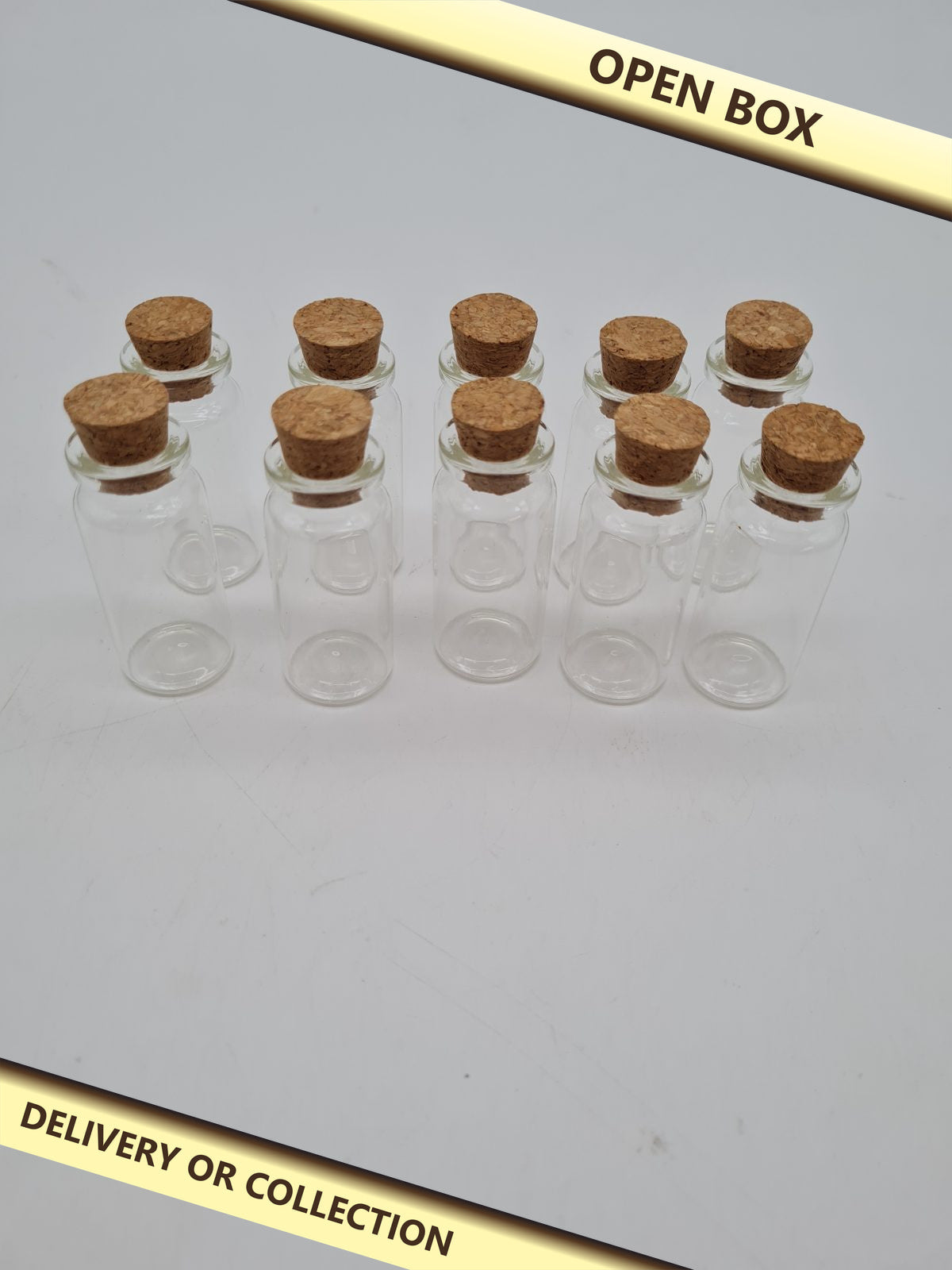 10 Small Glass Vials with Cork Stoppers — photograph 1 — Open box; auction delivery information shown on image
